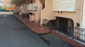 A covered outdoor area with a brick pathway leading to a building with a stone facade and multiple windows. - Hotel HUG-HUG KYOTO - Adults only (Kyoto)
