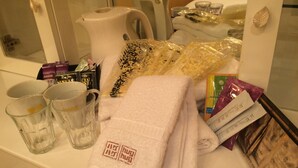 A hotel room with a white countertop, a kettle, a coffee maker, a towel, and various toiletries. - Hotel HUG-HUG KYOTO - Adults only (Kyoto)