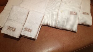 A brown leather couch with neatly folded white towels and a white robe with a button and embroidered text. - Hotel HUG-HUG KYOTO - Adults only (Kyoto)