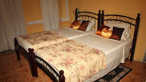A double bed with floral bedspreads, a wooden headboard, and a matching footboard. - Villa Shalom Guest House (Port of Spain)