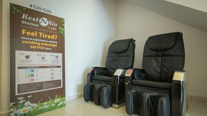 Een ruimte met massage stoelen en een bord waarop een ontspannende massage aangeboden wordt.