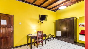 A room with a wooden door, a desk with a chair, a television mounted on the wall, and a wardrobe. - Par May La's Inn (Port of Spain)