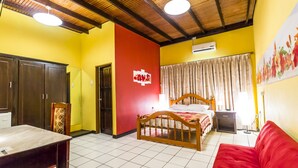 A room with a bed, a red sofa, a wooden table, and a wardrobe. - Par May La's Inn (Port of Spain)