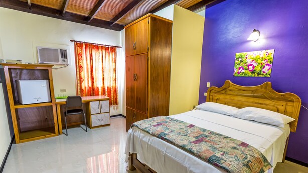 A bedroom with a bed, a desk with a chair, a wardrobe, and an air conditioner. - Par May La's Inn (Port of Spain)