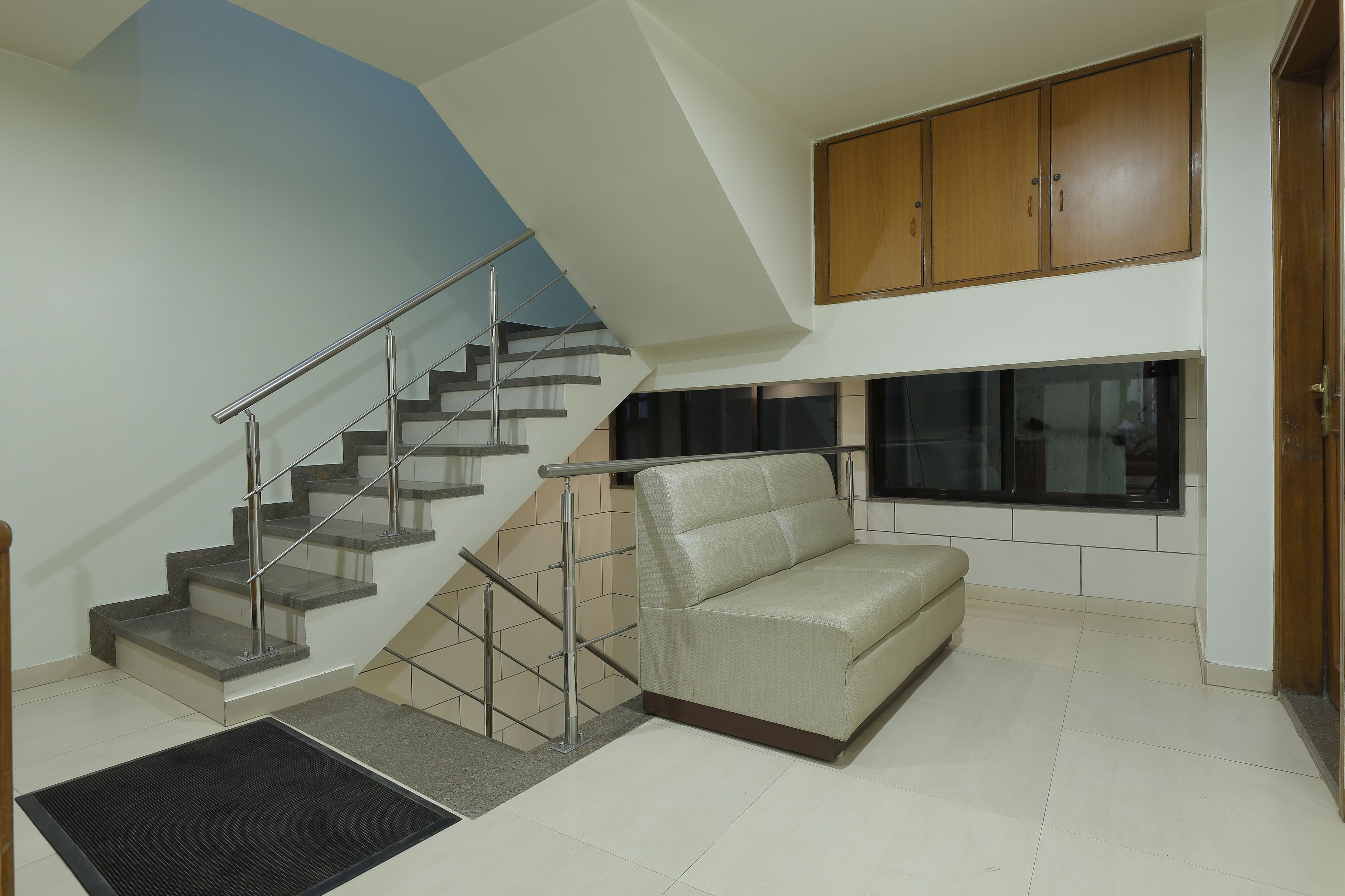 Una sala de estar moderna con una escalera, un sofá y un ventanal grande.