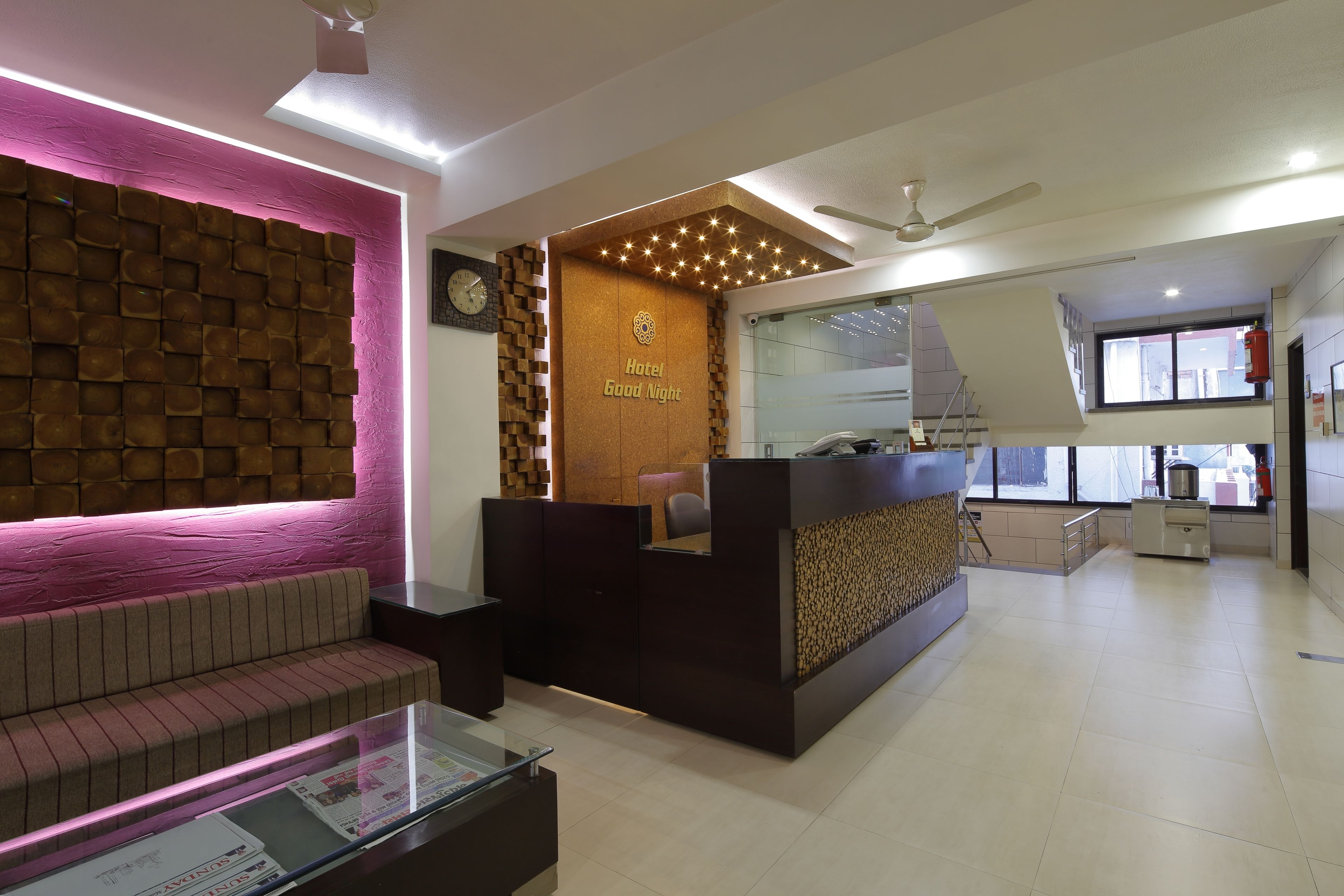 A hotel reception area with a modern design, including a reception desk, seating area, and a clock on the wall.