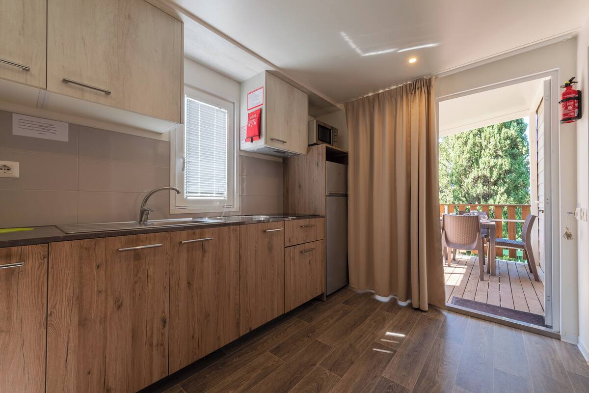 Een moderne keuken met houten kastjes, een roestvrijstalen spoelbak en een ingebouwde magnetron.