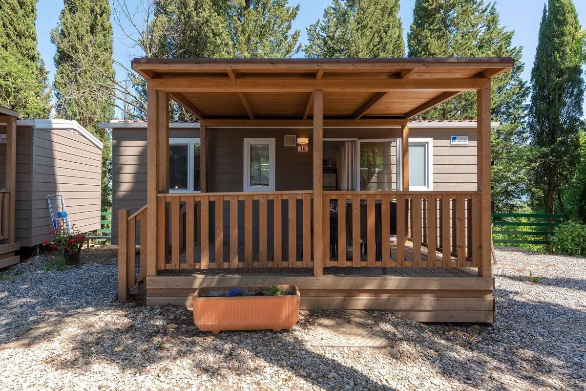 Een houten hut met een veranda, een raam en een deur.
