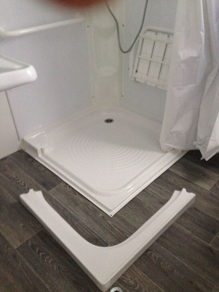 A bathroom with a shower area, a white bathtub, and a wooden floor.