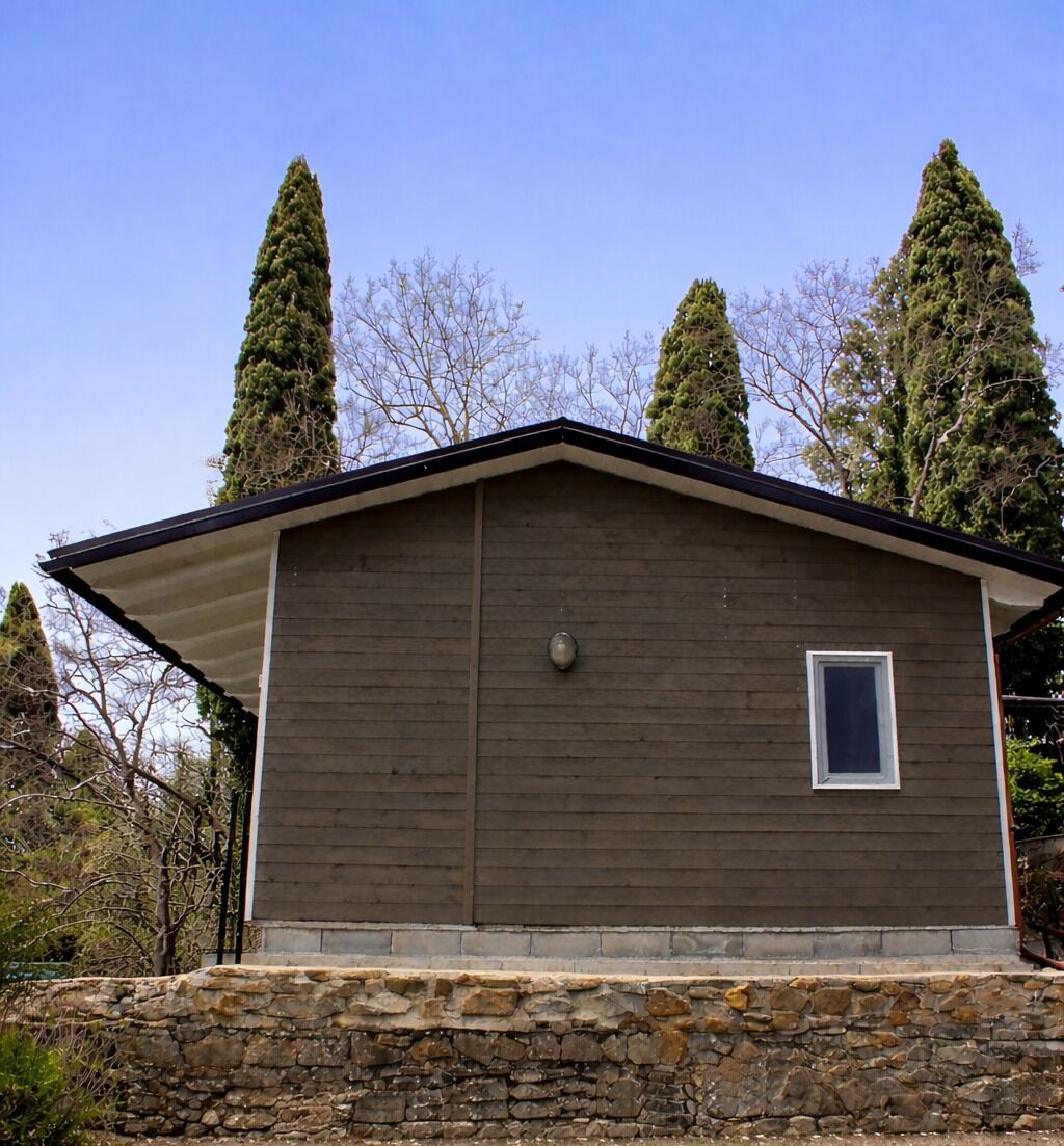 Un edificio de un piso con base de piedra, techo plano y una pequeña ventana en la pared frontal.