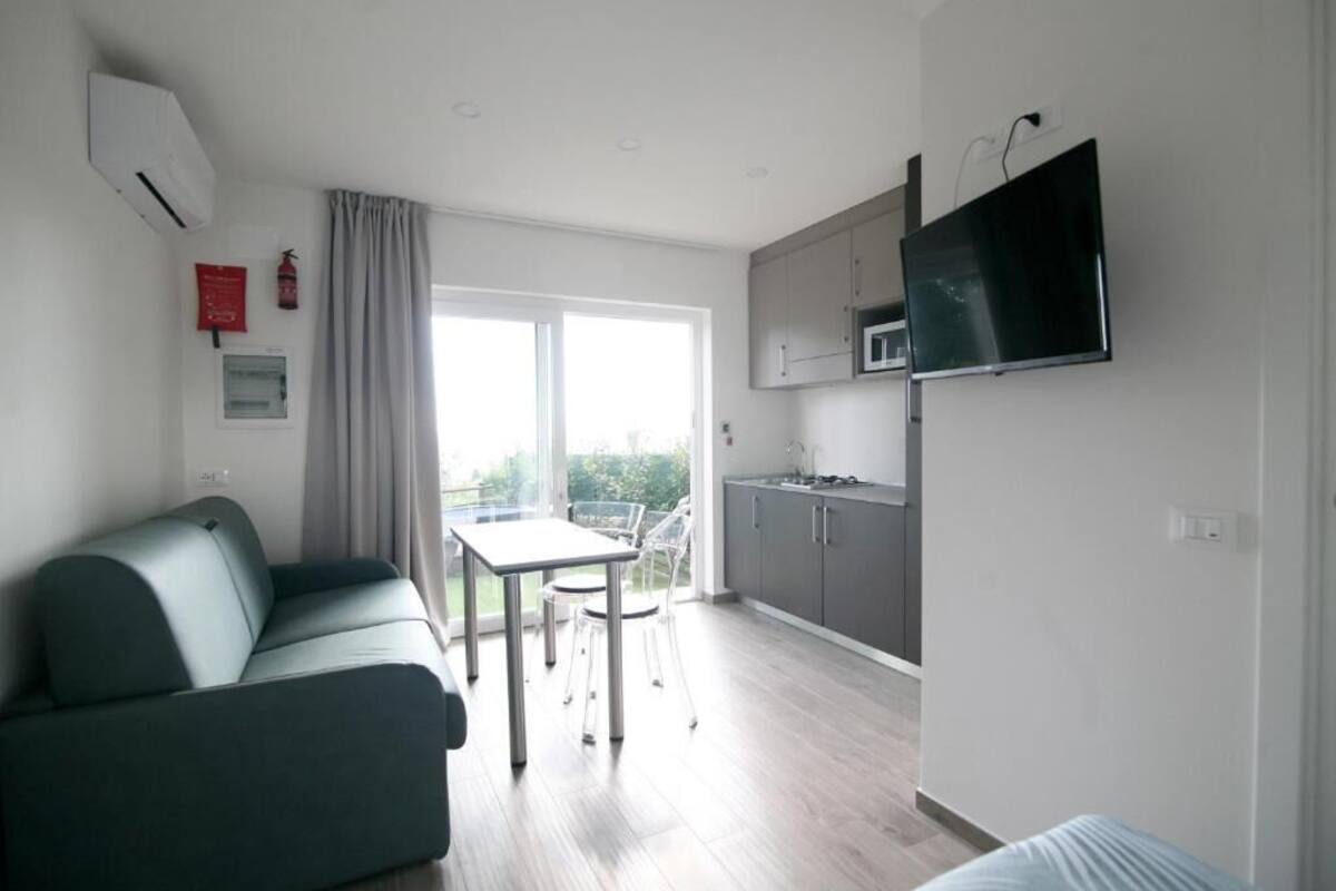Een modern appartement met een woonkamer, kitchenette en balkon.
