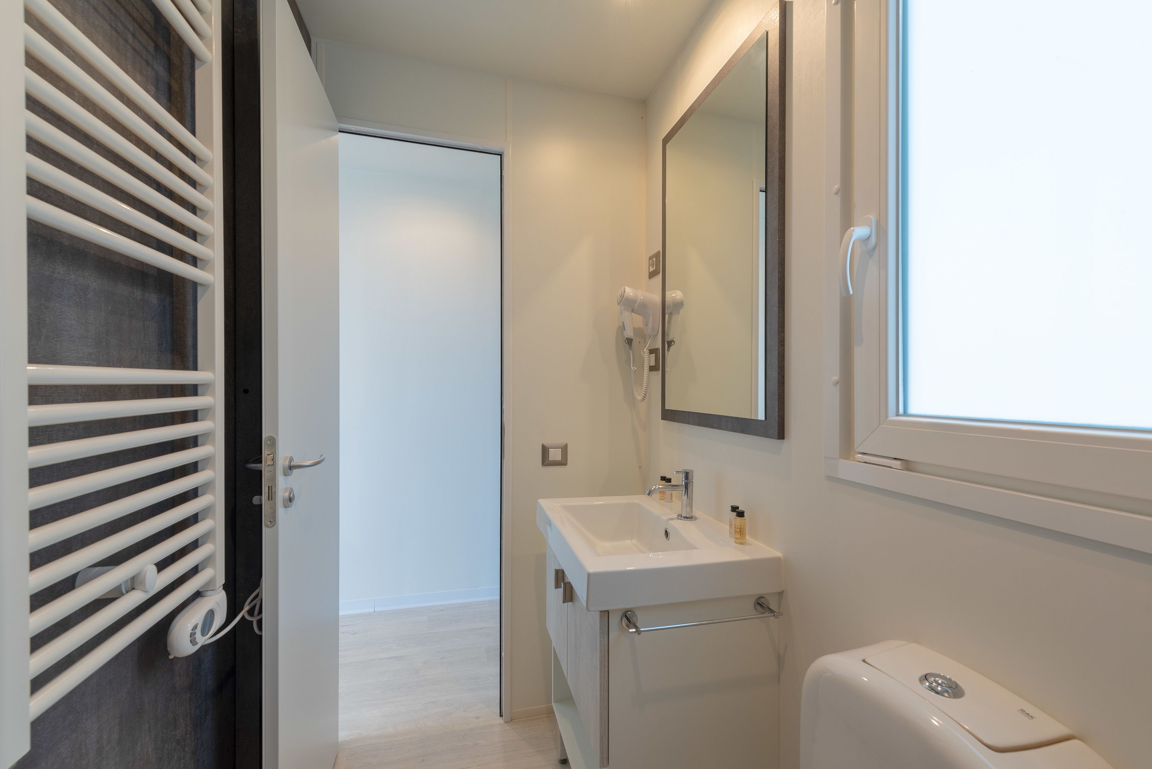 Ein modernes Badezimmer mit Waschbecken, Spiegel und Toilette in Weiß.