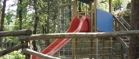 Une aire de jeux avec un toboggan en bois et une structure d’escalade.