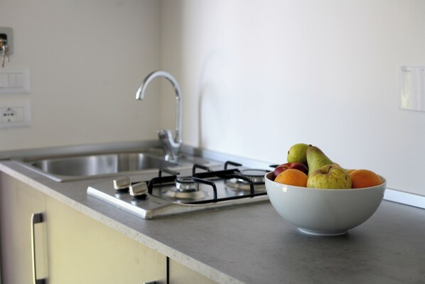 Una cocina con estufa a gas, un fregadero y un bol de fruta en la encimera.