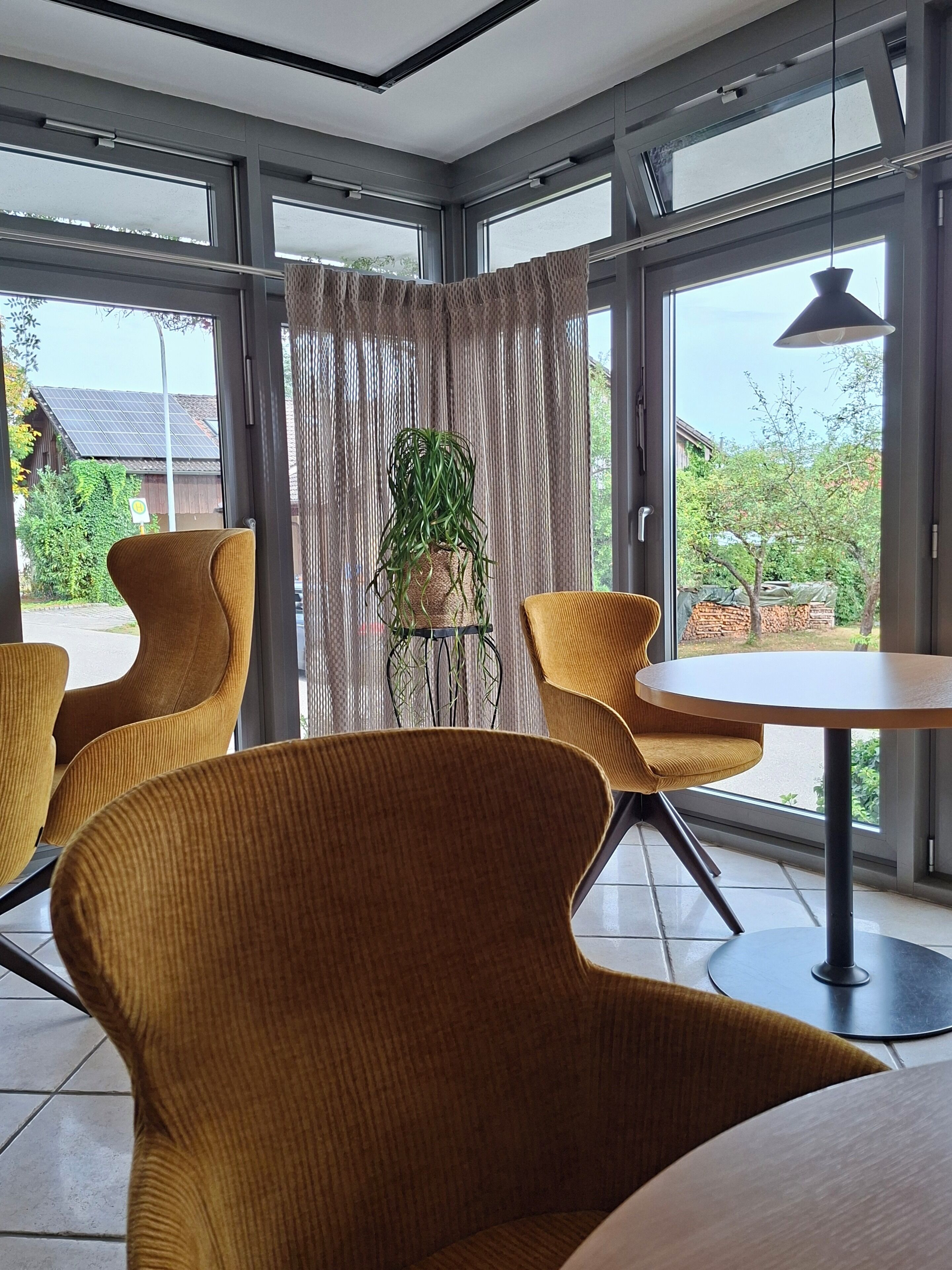 Een modern interieur met grote ramen, een ronde tafel en bijpassende stoelen.