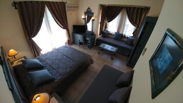 Una habitación de hotel con una cama grande, un sofá, un escritorio y un televisor.
