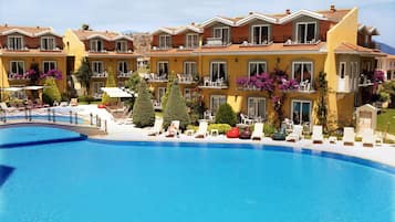 Un hotel con piscina, varios balcones y zonas de estar al aire libre.