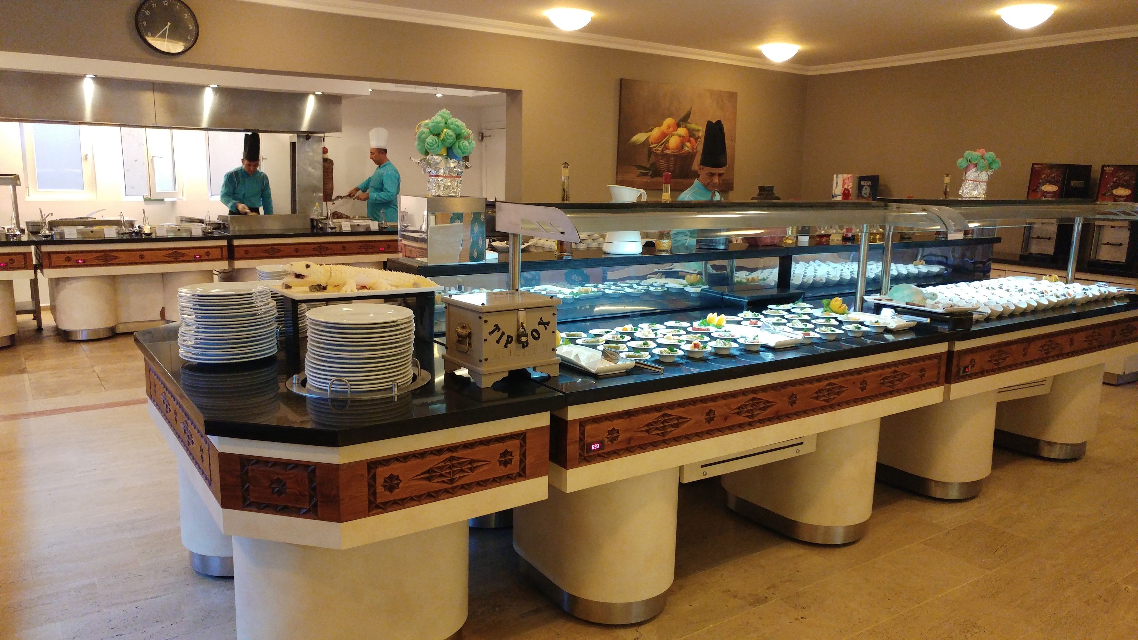 A buffet setup with multiple food stations, a clock on the wall, and a decorative vase.