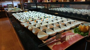 Un bufé con diversos alimentos y salsas dispuestas en cuencos.