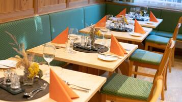 A restaurant with wooden tables and green cushioned booths.