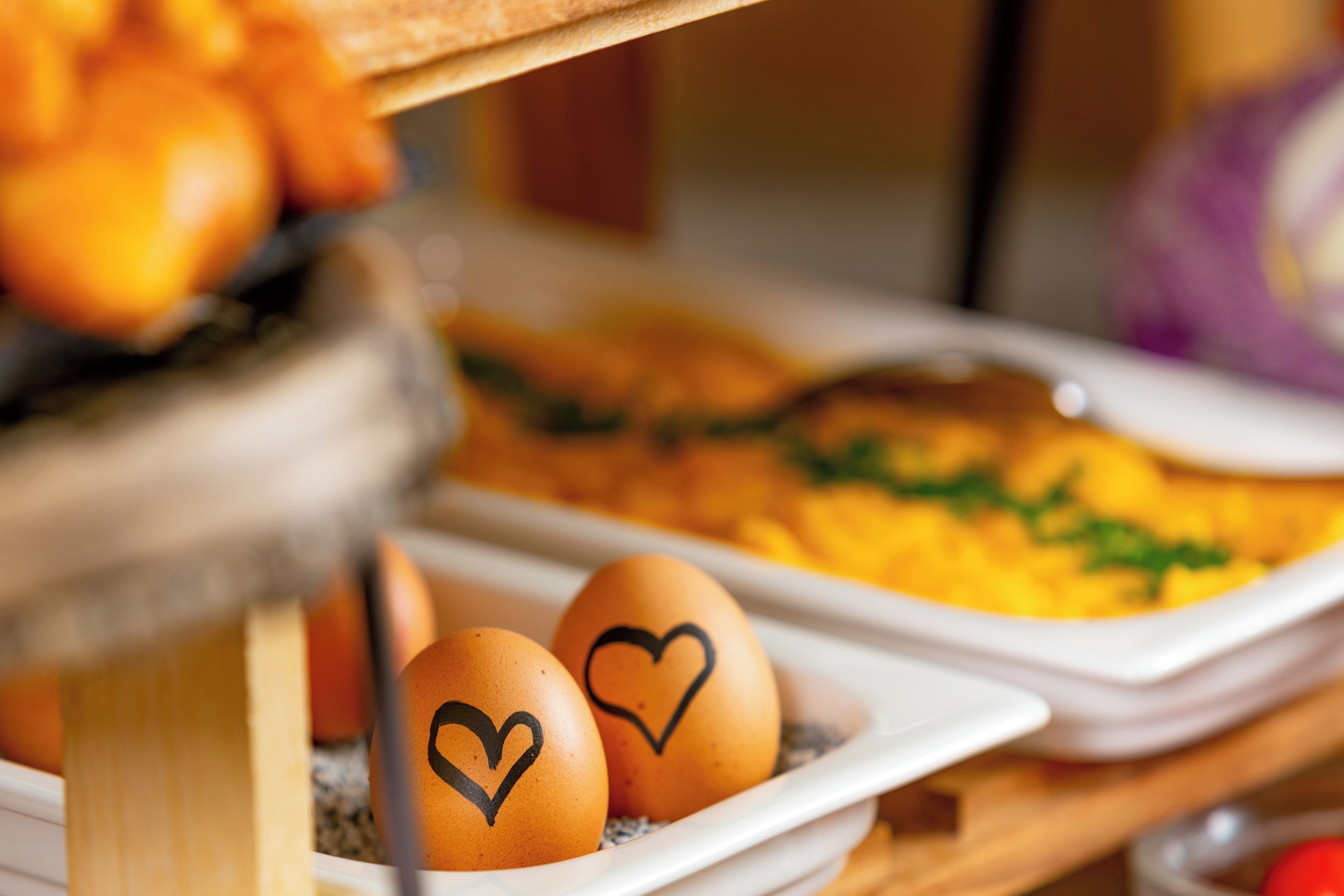 A breakfast buffet with eggs and a dish with green garnish.