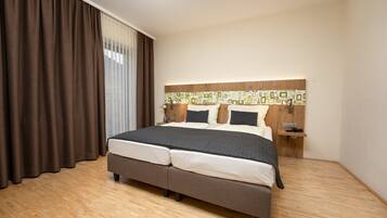A modern hotel room with a large bed, wooden flooring, and a decorative wall panel.