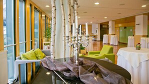 Eine moderne Hotellobby mit Glastisch, einem Kerzenleuchter, einem grünen Stuhl und einem Tisch mit weißer Tischdecke.