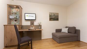 A reception area with a wooden desk, a computer, a chair, a sofa, and a framed picture on the wall.