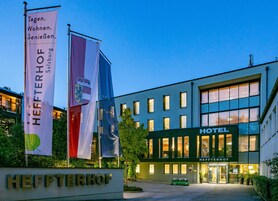 Hotel HEFFTERHOF con insegna, bandiere e facciata con finestre.