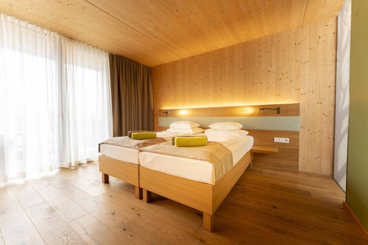 Een slaapkamer met houten lambrisering, een groot bed, een nachtkastje en een nachttafeltje.