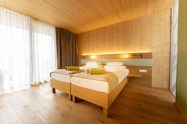 A wooden-paneled bedroom with a large bed, a bedside table, and a nightstand.