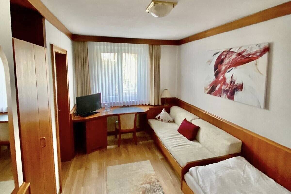 Ein kleines Zimmer mit einem Bett, einem Schreibtisch und einem Schlafsofa.