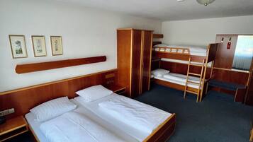 Habitación de hotel con una cama grande, una cama más pequeña, un armario, un escritorio y una litera.