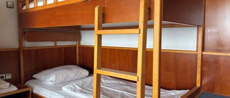 A bunk bed with a ladder, a bedside table, and a small shelf.