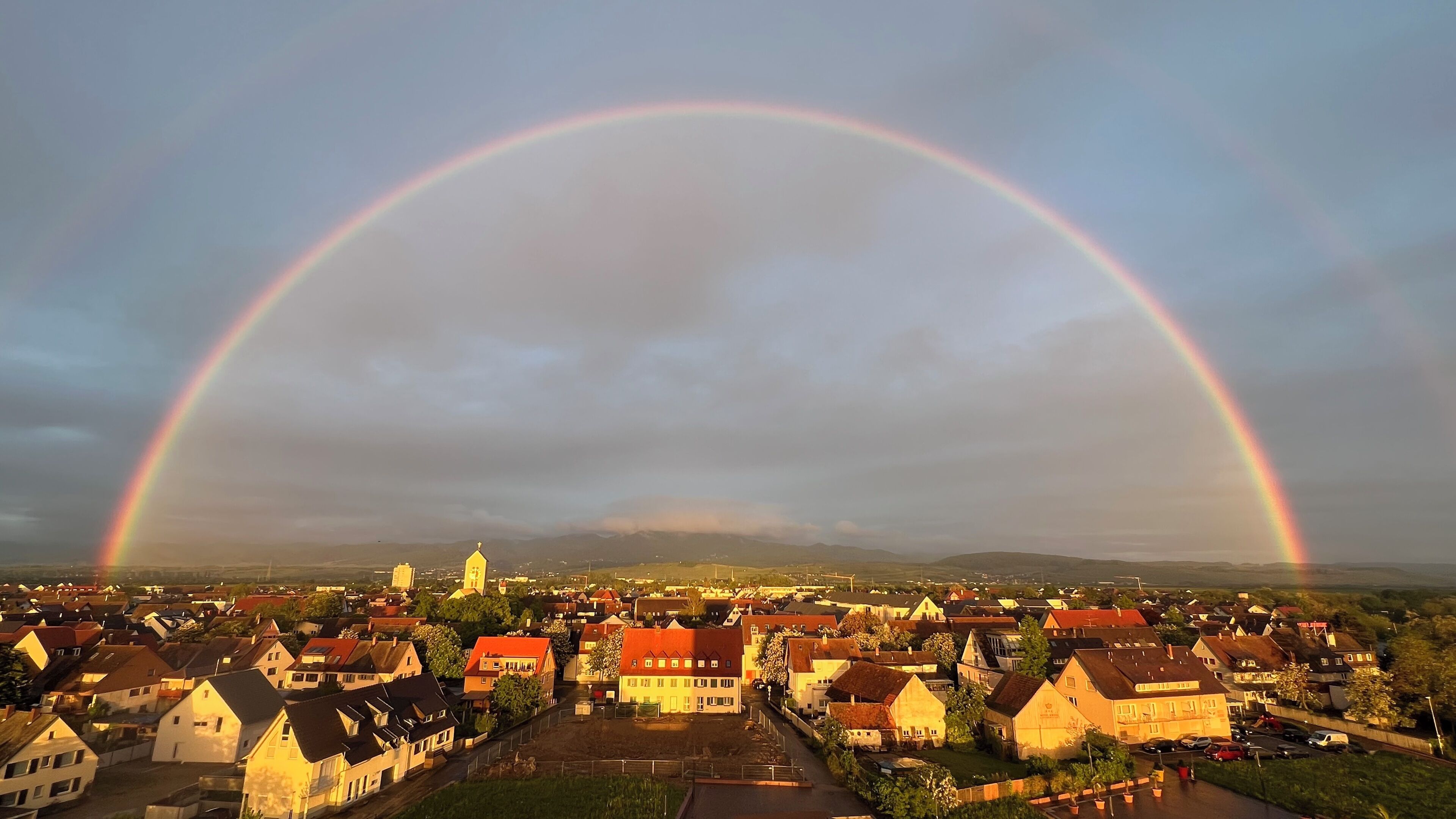 A town with a prominent rainbow arching over it.