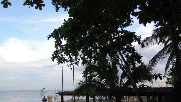 Zona de estar al aire libre con mesas y sillas, con vista al mar.