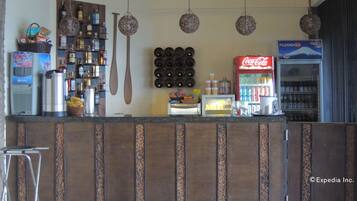 A bar area with a counter, shelves with bottles, a Coca-Cola fridge, and a Fujidenzo fridge.