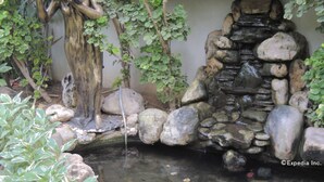 Un jardín con fuente de agua, que incluye una estatua y una cascada de piedra.