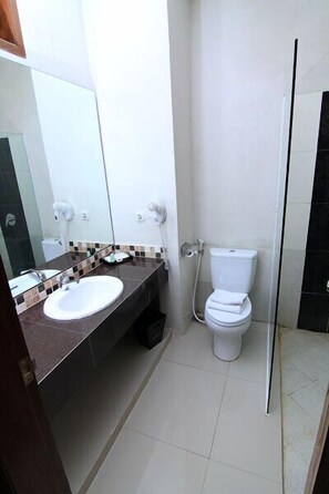 A bathroom with a white sink, a mirror, a toilet, and a shower area. - The Gambir Anom Hotel Resort & Convention (Ngemplak)