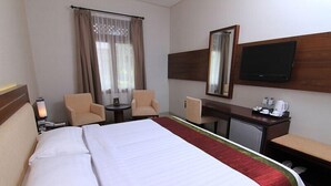 Une chambre d’hôtel équipée d’un grand lit, d’un bureau, d’une chaise, d’une télévision et d’une machine à café.