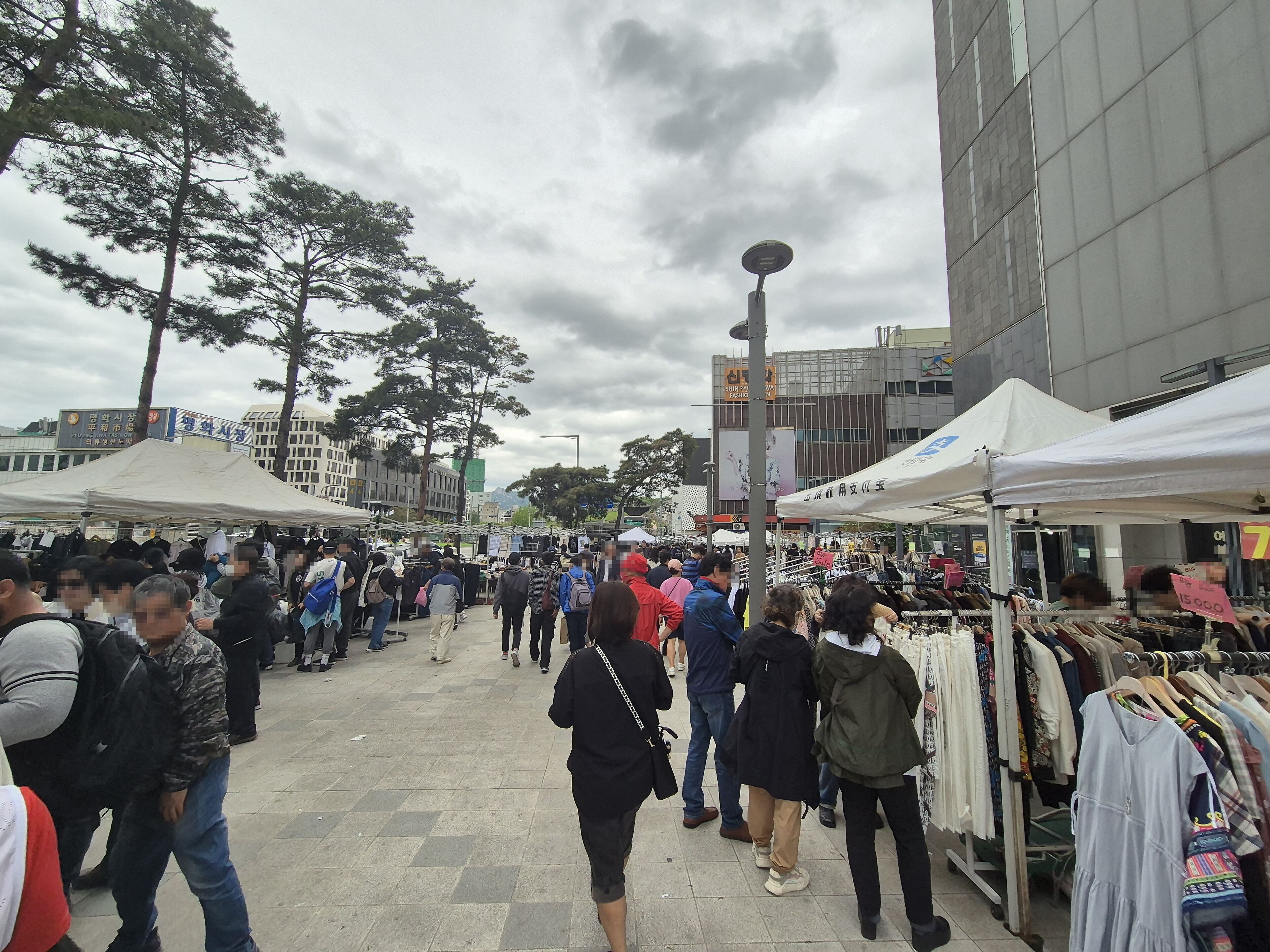 A crowded outdoor market with people browsing stalls.