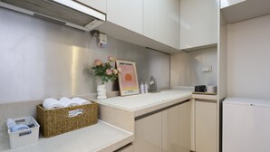 Una cocina moderna con encimera blanca, cesta de mimbre y un cuadro enmarcado de la obra 'Sunset' de Andy Warhol.