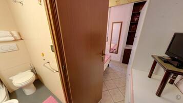 Un bagno con un water, un bidet e delle maniglie di sostegno.