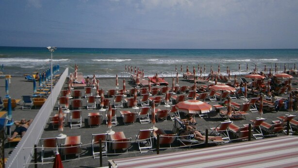 A beachside hotel with rows of sun loungers and umbrellas, a pool area, and a view of the ocean. - Hotel Giordana (Loano)