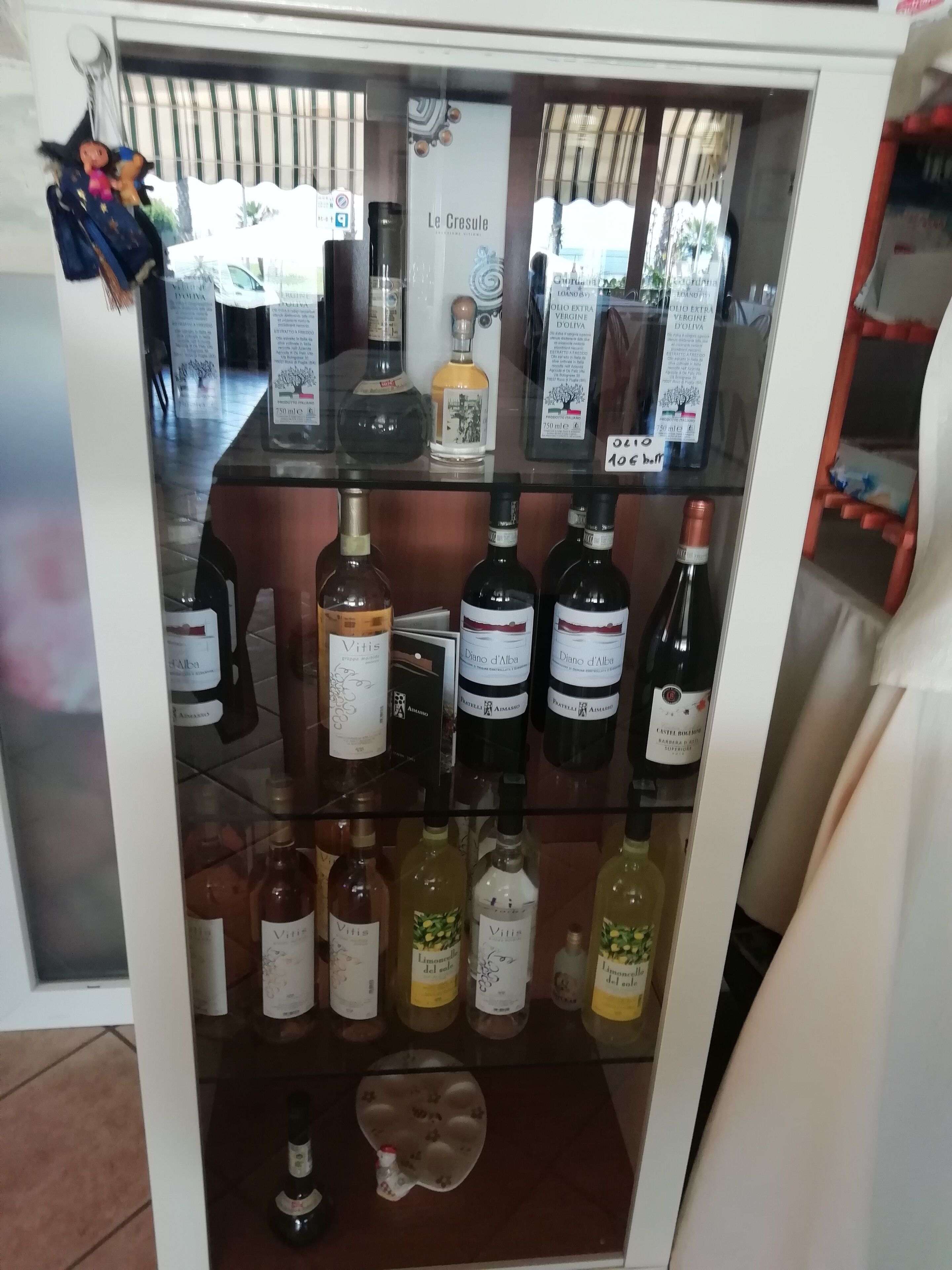 Una vetrina per vini con diverse bottiglie e alcuni elementi decorativi.