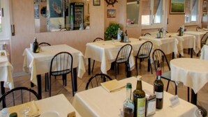 A restaurant with multiple tables, chairs, and a variety of bottles on the tables. - Hotel Giordana (Loano)