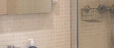 Un baño con lavamanos blanco, un espejo y zona de ducha.