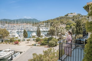 A balcony with a view of a marina, boats, and a hill with buildings. - Appartements de l'Hélios - Îles des Embiez (Six-Fours-les-Plages)