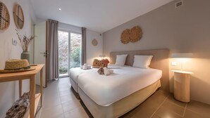 A modern bedroom with a large bed, bedside tables, a lamp, and a view of the outdoors. - Appartements de l'Hélios - Îles des Embiez (Six-Fours-les-Plages)