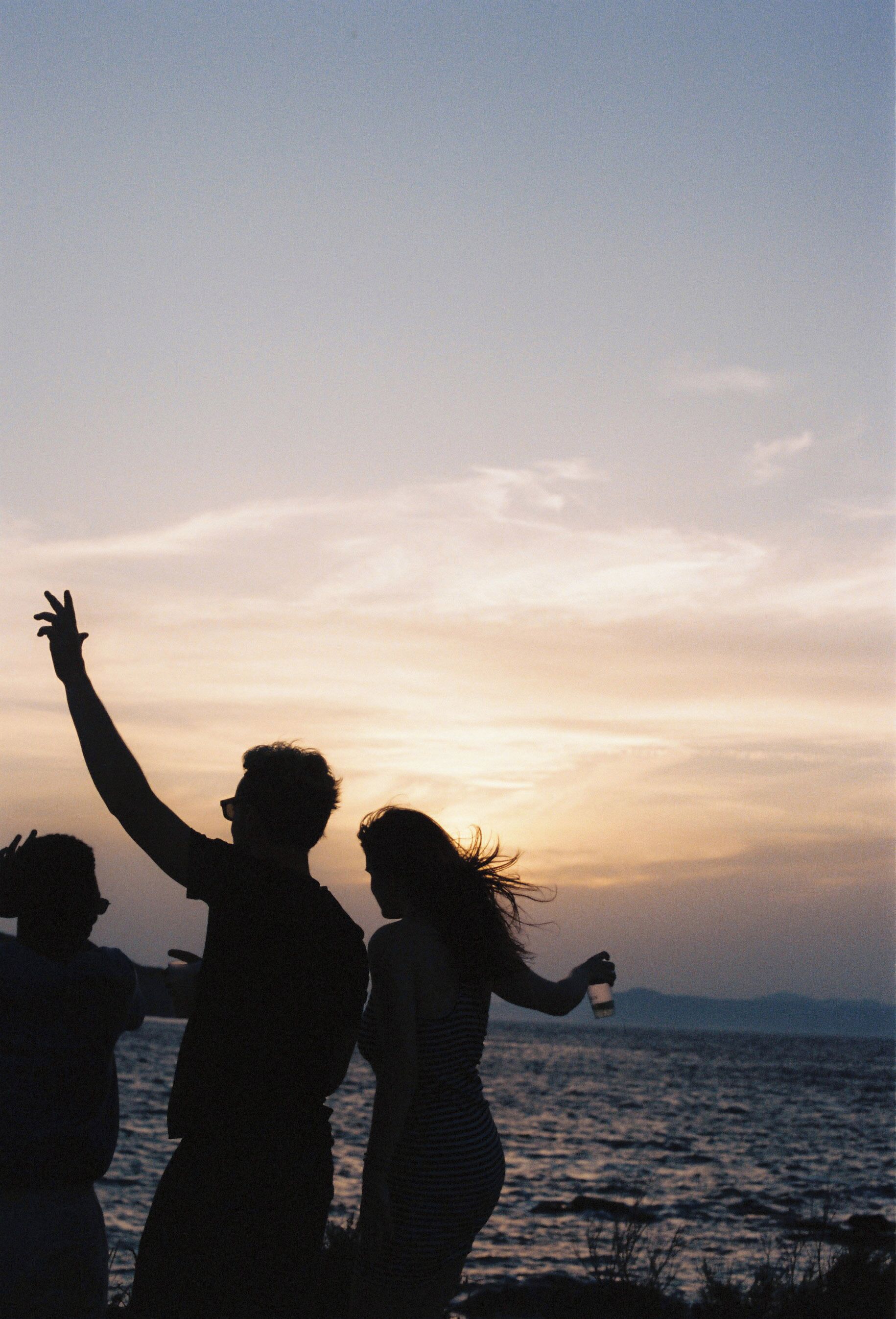 Des silhouettes de personnes se découpent sur le ciel au coucher du soleil.